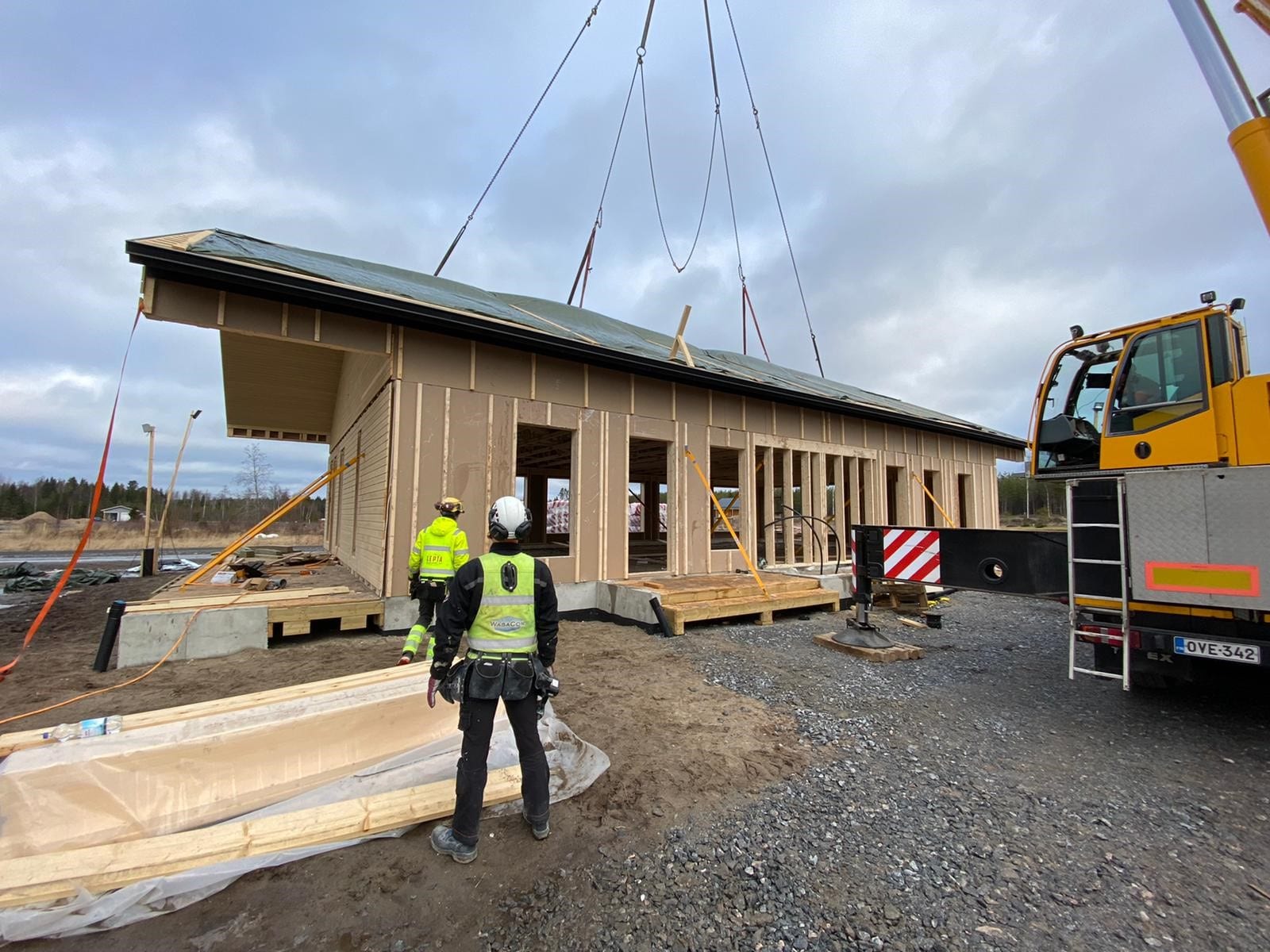 Ulkokuva rakennettavasta talosta, kattoa nostetaan paikoilleen.